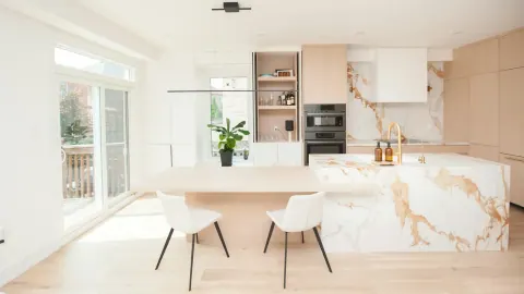 Bright contemporary kitchen with a dramatic stone waterfall island and full-height backsplash