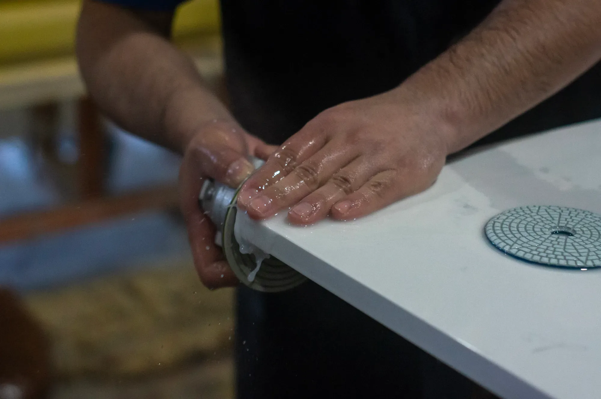 Artelye fabricator hand-polishing the edge of a white countertop