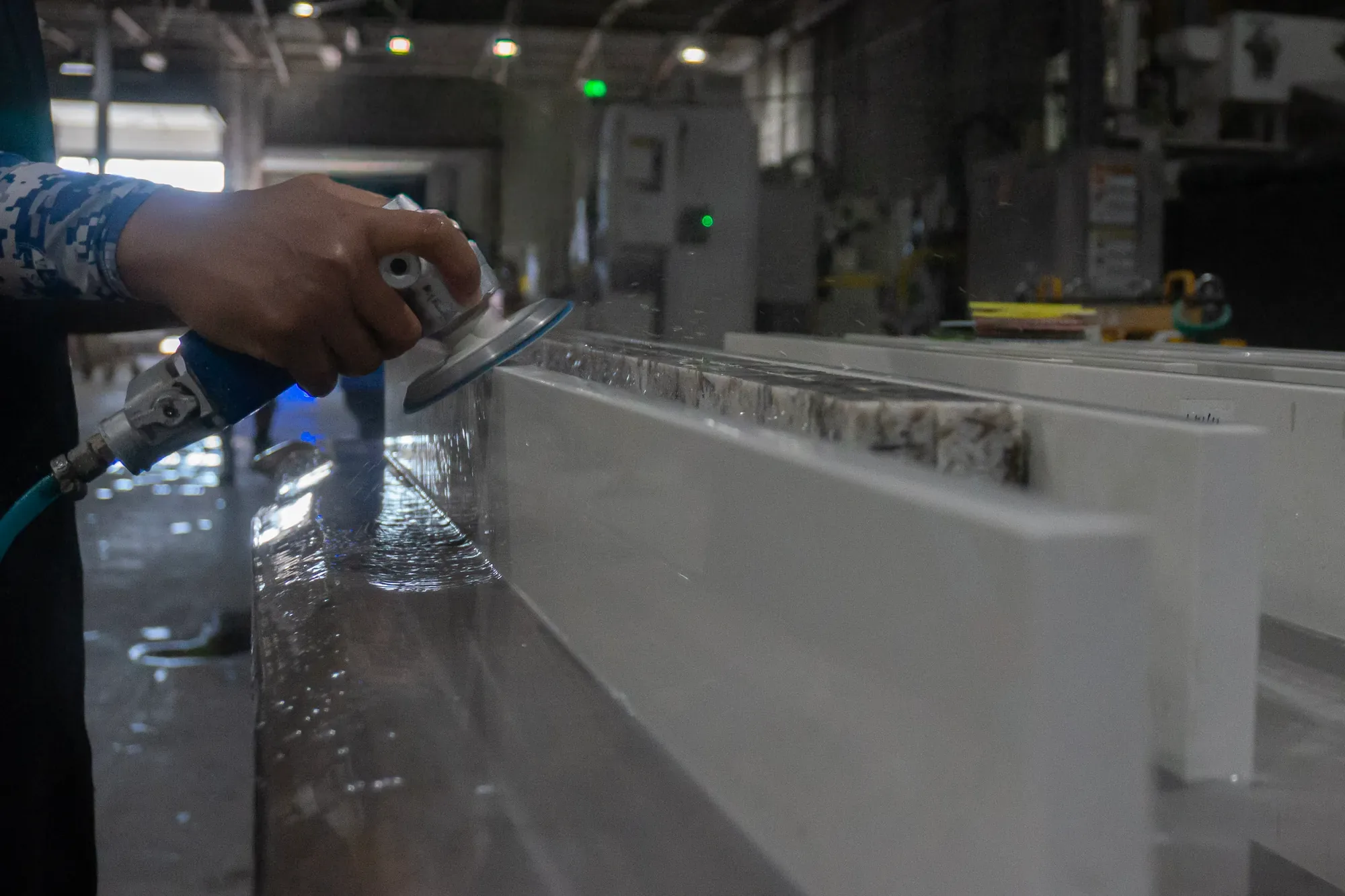 Artelye fabricator wet-finishing and inspecting a white countertop edge