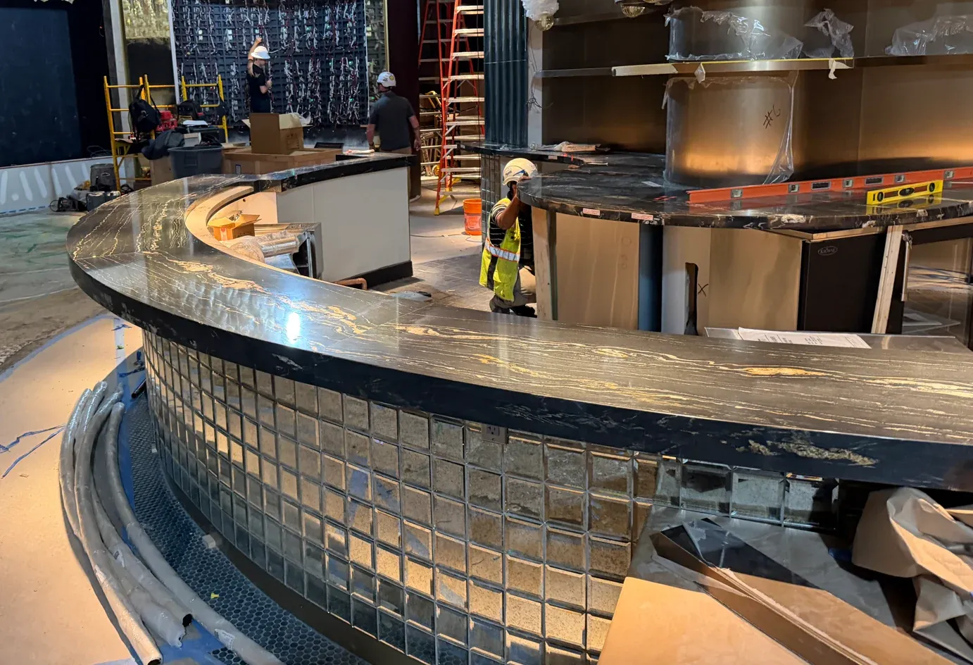 Dark stone countertop following the curved tiled front of the casino bar
