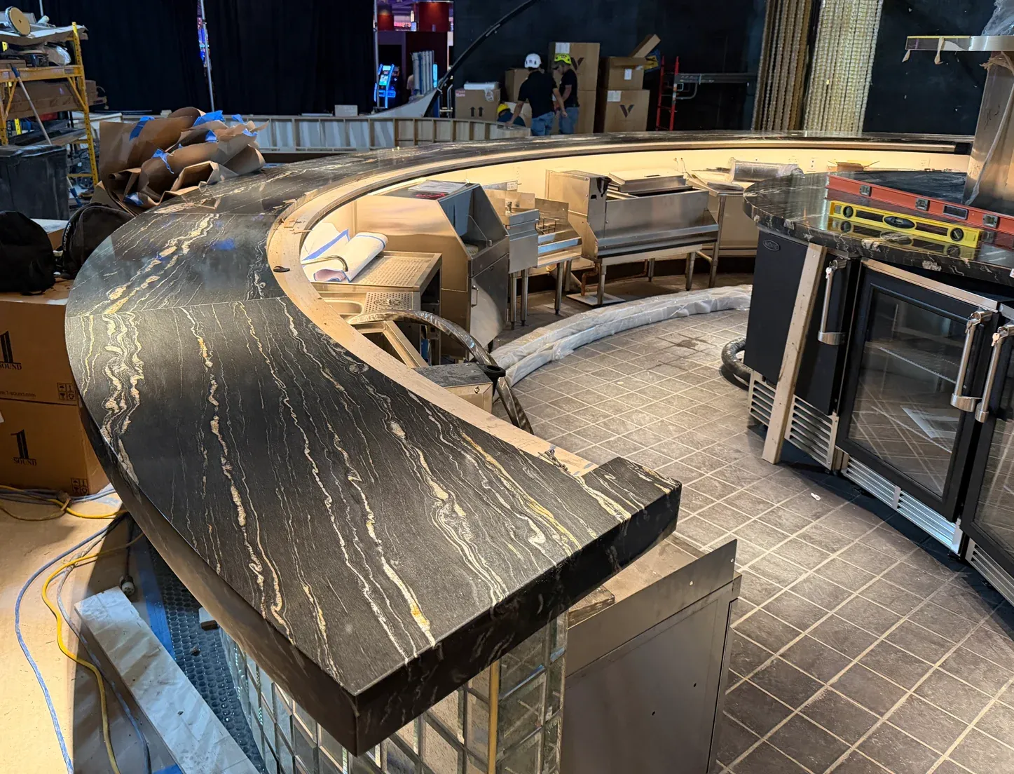 Sweeping dark natural-stone bar with pale veining at MD Live Casino during installation