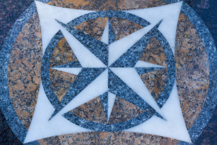 a geometric star-shaped floor medallion made of granite and marble for a commercial building entry