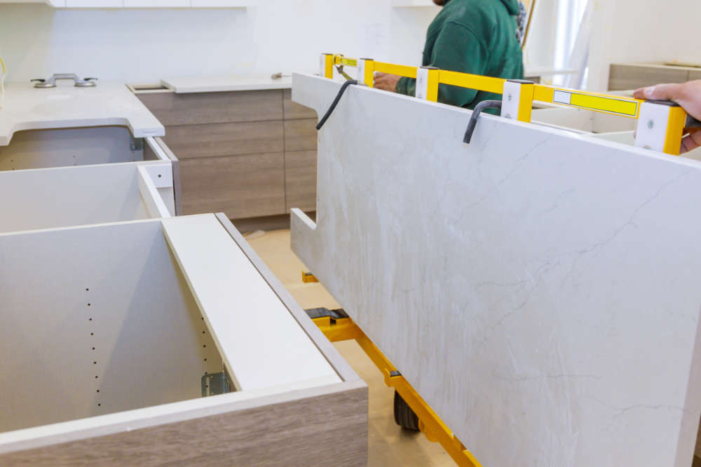 Granite installers lifting new countertops without replacing the cabinets