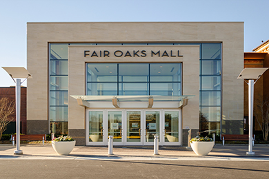 The modern stone and glass entrance of the Fair Oaks Mall on a sunny day